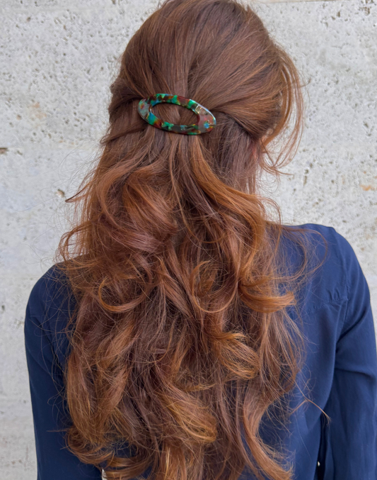 Person with long, wavy hair wearing a decorative hair clip against a neutral background