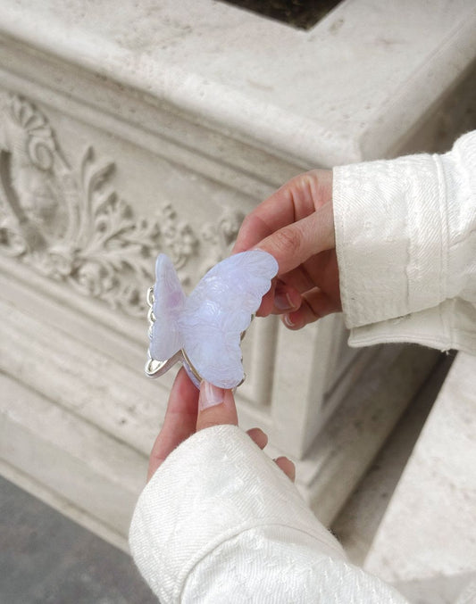 Person holding a butterfly-shaped object in front of a decorative stone wall.
